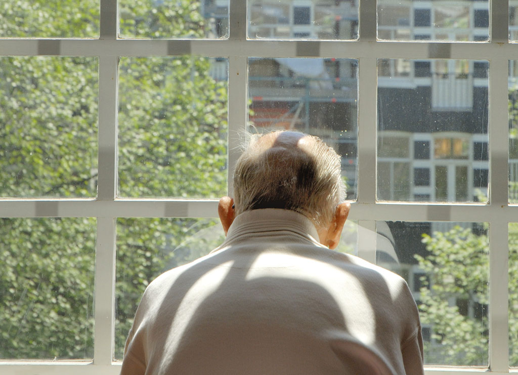 senior man alone in front of window