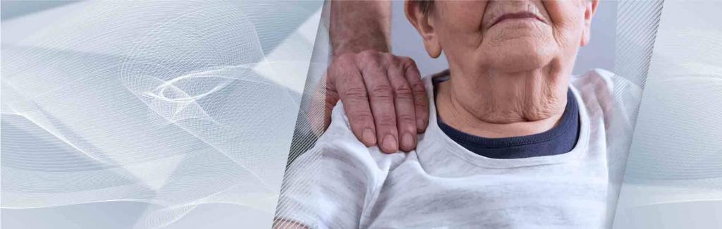 Adult day care caregiver with reassuring hand on seniors shoulder