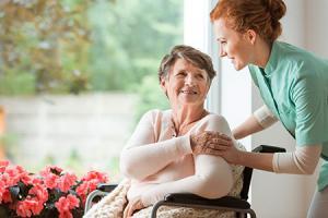 Young nurse helping an elderly woman in a wheelchair. Nursing home concept