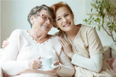 Nurse hugging grandma smiling in a senior care setting