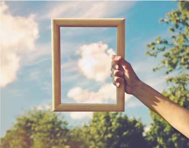 Hand holding a picture frame, framing a cloud in the sky 