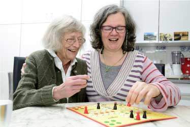 Mom and daughter having fun playing a board game in one of our Residential Care Homes