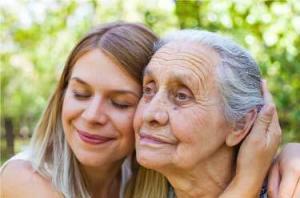 Close up picture of senior disabled woman with loving granddaughter in the garden